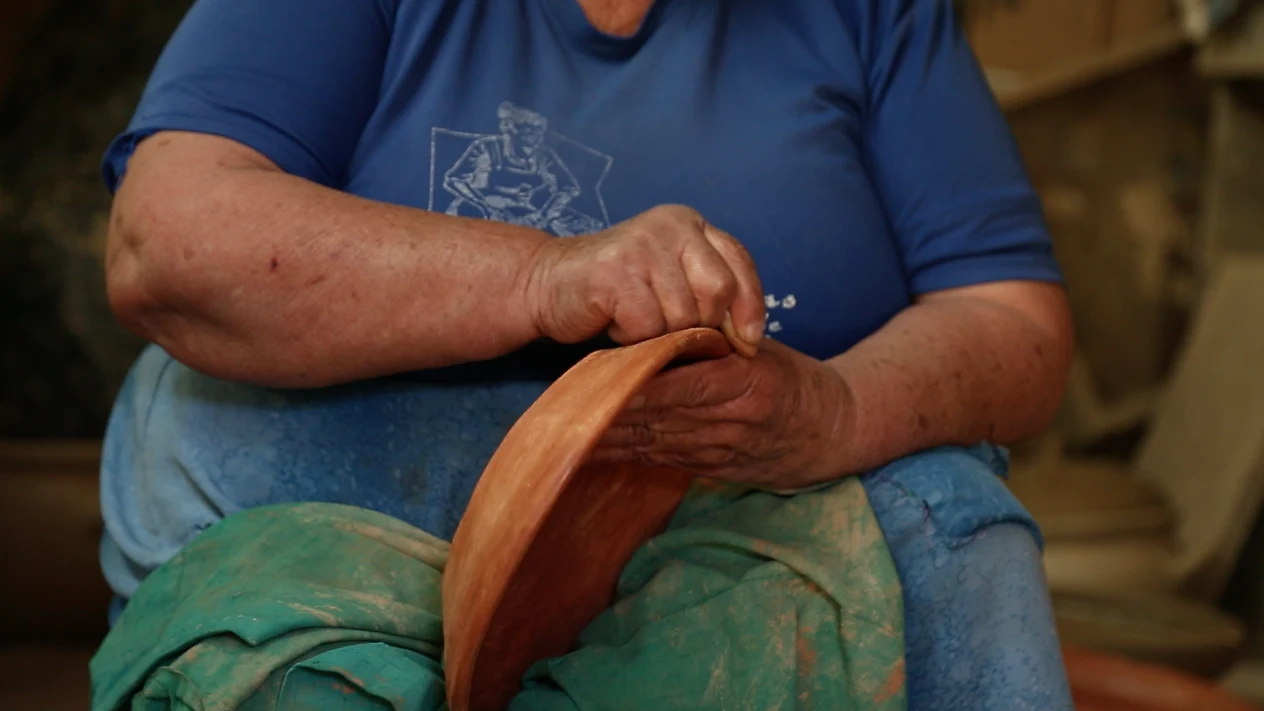 Manos de una locera de Pilén bruñendo una pieza de greda.